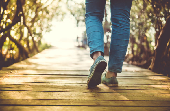 Legs of a young adult patient with XLH walking along a wooden path